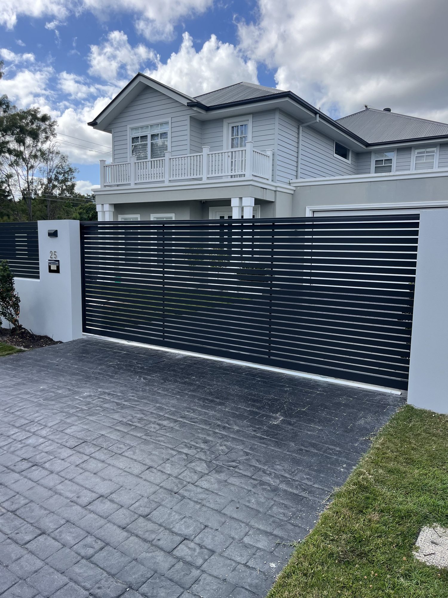 Black horizontal-slat automatic aluminium sliding gate at a Brisbane home